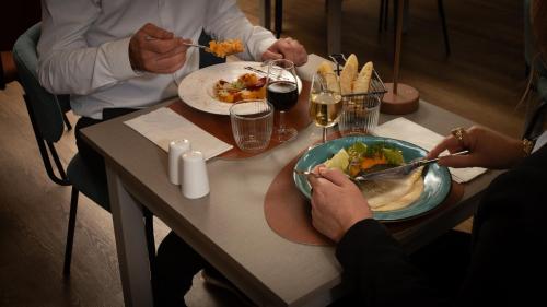 a group of people sitting at a table eating food at Hôtel Nell in Saint-Marcel