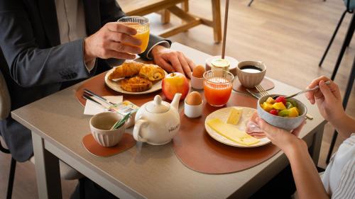 a group of people sitting at a table eating breakfast at Hôtel Nell in Saint-Marcel