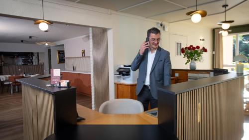 a man talking on a cell phone in an office at Hôtel Nell in Saint-Marcel