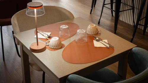 a table with a lamp and utensils on it at Hôtel Nell in Saint-Marcel