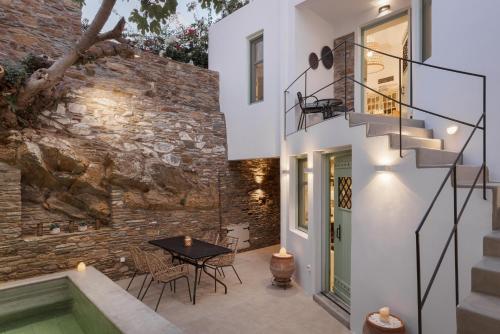 a patio with a table and stairs next to a brick wall at Porto Sereno Andros Suites in Andros