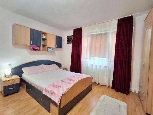 ein Schlafzimmer mit einem Bett und einem Fenster mit roten Vorhängen in der Unterkunft Apartament 2 Camere, Etaj 1 in Buzău