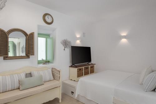 a bedroom with a bed and a tv on the wall at Porto Sereno Andros Suites in Andros