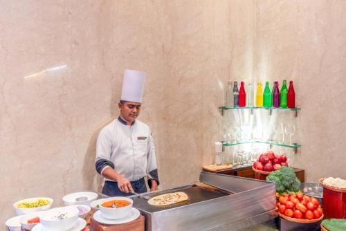 a chef standing in a kitchen preparing food at Pride Plaza Hotel, Kolkata in Kolkata