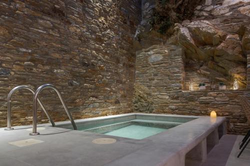 a bath tub in a room with a stone wall at Porto Sereno Andros Suites in Andros