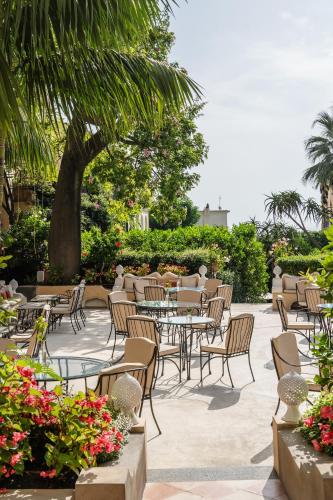a patio with tables and chairs and a tree at Hotel Palazzo Murat in Positano