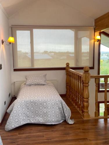 a bedroom with a bed and a large window at Casa Las Lengas in Puerto Natales