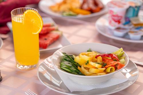 a bowl of salad and a glass of orange juice at Solaris Apartman&Resort in Cserkeszőlő