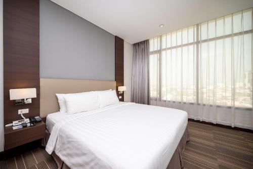 a bedroom with a large bed and a large window at Fortune Hotel Korat- SHA Plus in Nakhon Ratchasima