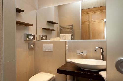a bathroom with a sink and a toilet and a mirror at Hotel Kreuz & Post Grindelwald in Grindelwald