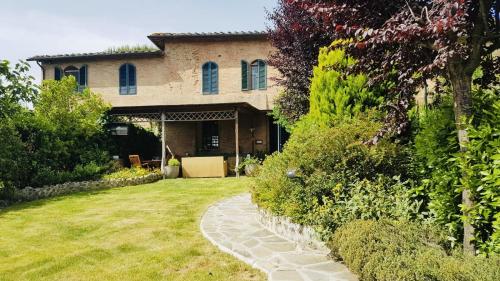 a house with a stone walkway in front of a yard at La dogana in Siena