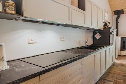 a kitchen with white cabinets and a black counter top at Agriturismo Angelino - Giazza Ljetzan in Selva di Progno
