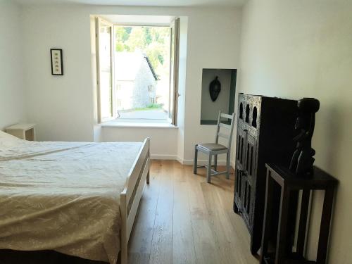 une chambre avec un lit, une fenêtre et une chaise dans l'établissement gentilhommière de Saint Amandin, à Saint-Amandin