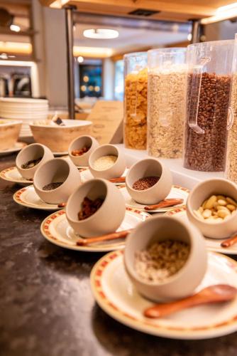 a counter topped with plates of food and bowls of cereal at Hotel Kreuz & Post Grindelwald in Grindelwald