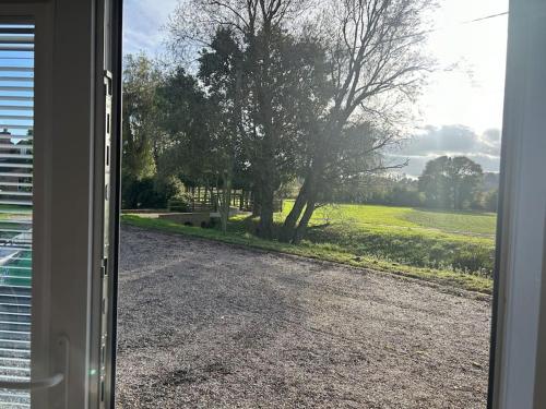 a door open to a driveway with a tree at Spitfire View in Aldington