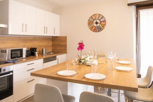 a kitchen with a table with chairs and a clock on the wall at Le Luminosa - Centre Ville - 6 pers in Haguenau