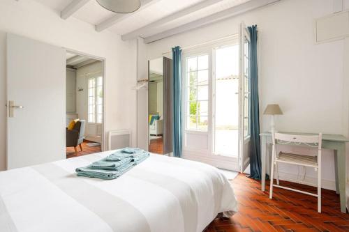 une chambre blanche avec un lit et un bureau dans l'établissement Cottage au calme avec terrasse et jardin, à Villegouge