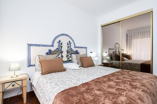 una camera da letto con un grande letto e un grande specchio di Parque dos Reis Apartment a Monte Gordo