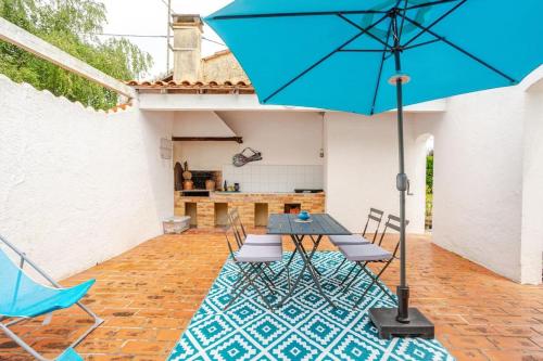 d'une terrasse avec une table, des chaises et un parasol bleu. dans l'établissement Cottage au calme avec terrasse et jardin, à Villegouge