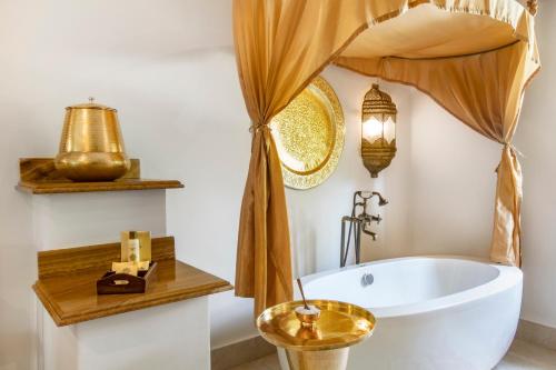 baño con bañera blanca y un bol de oro en Baraza Resort and Spa Zanzibar, en Bwejuu