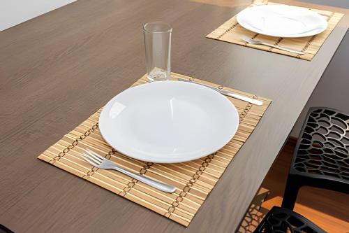 a white plate on a bamboo napkin on a table at Flats Osasco Trade Center in Osasco