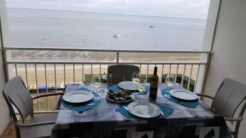 - une table avec des assiettes et des verres à vin et une vue sur la plage dans l'établissement T2 Les pieds dans l'eau, à Arcachon