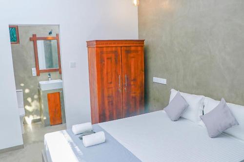 a bedroom with a large bed with a wooden cabinet at Kelly Ahangama in Ahangama