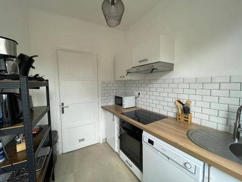 une cuisine avec un évier et une cuisinière four supérieur dans l'établissement Appartement Emeraude 2 pers - L'Artdu'Net -, à Sedan