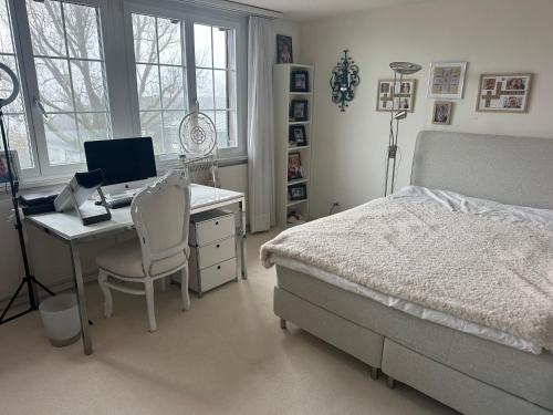 a bedroom with a bed and a desk with a computer at Luxusvilla nahe Zürichsee in Hombrechtikon