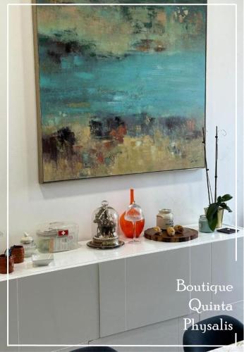 a white shelf with a painting on the wall at Boutique Quinta Physalis in Fenais da Luz