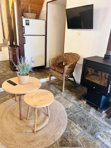 un soggiorno con 2 tavoli e un camino di COZY VILLAGE HOUSE ΑΓΙΟΣ ΛΑΥΡΕΝΤΙΟΣ ΠΗΛΙΟΥ a Agios Lavredios