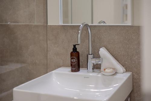 a bathroom sink with a bottle of soap on it at Apartments Hotel Stadt Hamburg in Westerland (Sylt)