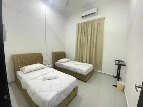 a bedroom with two beds and a mirror at Cerah Homestay in Kampong Gong Kempas