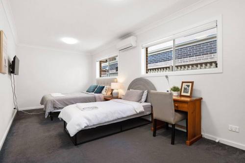 a bedroom with two beds and a desk and windows at KozyGuru | Austral | Convenient 4 x Ensuite House in Austral