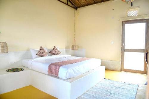 a bedroom with a white bed and a window at Vijay Bagh in Jaisalmer