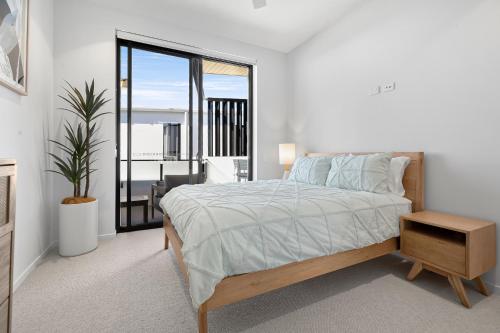 a white bedroom with a bed and a large window at Bokarina Beach Apartments, an Ascend Collection Hotel in Bokarina