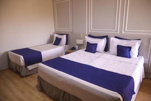 two beds in a hotel room with blue pillows at Laguna Plaza Hotel in Brasilia