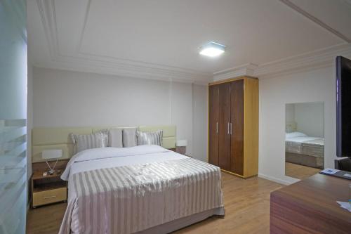 a bedroom with a large white bed and a television at Laguna Plaza Hotel in Brasilia