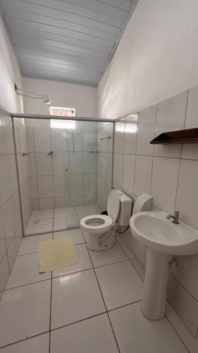 a white bathroom with a toilet and a sink at Pousada Arraial da Poesia in Arraial d'Ajuda