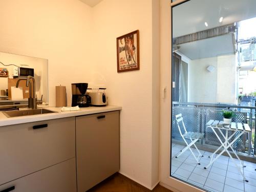 a kitchen with a counter and a balcony with a chair at Modern Apartment Near Kristalltherme- MontiRooms in Ludwigsfelde