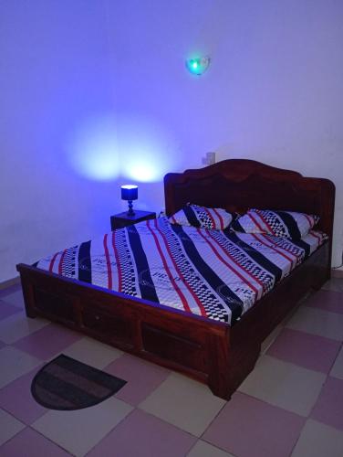 un letto con una struttura in legno in una stanza di Jrodait appart a Cotonou