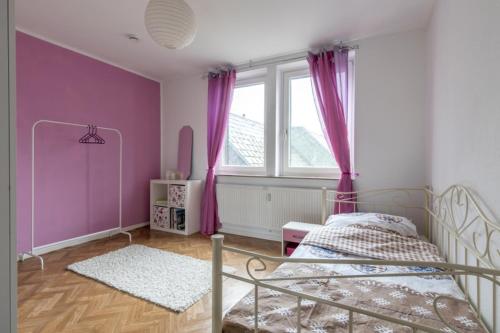 a bedroom with a bed with purple walls and a window at Private Rooms in Hannover