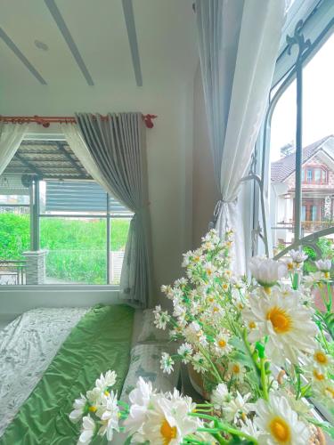 a room with a bed with a bunch of flowers at Nhà của Nâu - Homestay Đà Lạt in Da Thanh