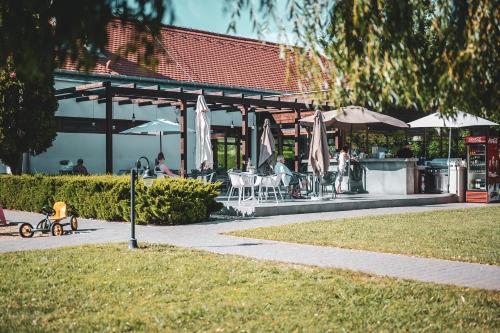 a building with tables and umbrellas and a child riding a bike at Hercegasszony Birtok in Mezőtúr