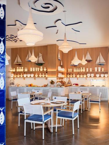 a restaurant with white tables and chairs and a counter at H10 Estepona Palace in Estepona