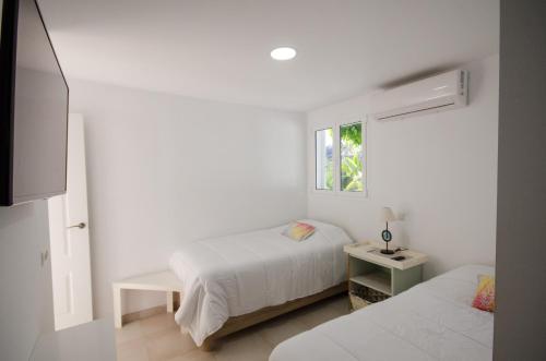 a white bedroom with two beds and a window at Terraced 2 bedroom beach rental in Maspalomas