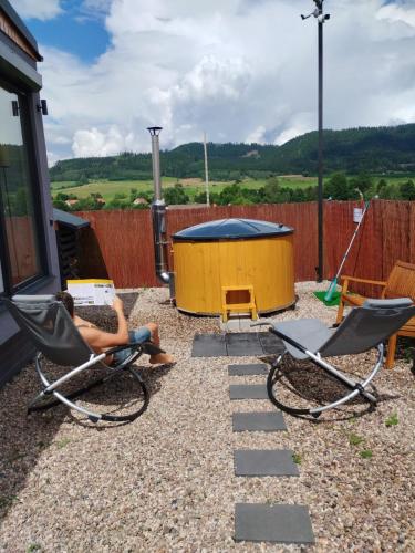 a person sitting in chairs in a backyard with a swing at Rajska polana Domki PREMIUM ,na odludziu z prywatną BALIĄ z jacuzzi i sauną ,Cisza,rowery elektryczne,góry,astroprzygoda,- Adršpach, Skalne Miasto, Zamek Książ,Andrzejówka,Karpacz, Śnieżka,Janskie Laznie,Pec in Mieroszów