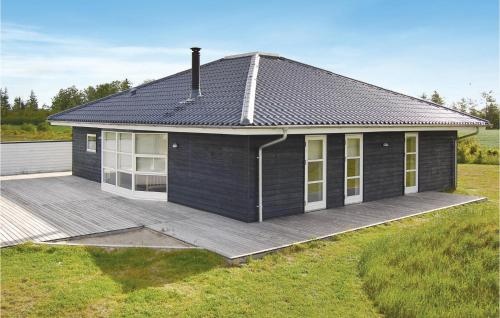 a small house with a wooden deck in a field at Holiday Home Stikkelsbærvej Tarm Iv in Hemmet