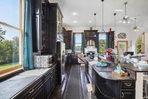 a large kitchen with black cabinets and windows at The Starlight Tower Manor, River, Arcades, Observatory, Theater in Fort Atkinson