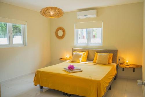 - une chambre avec un lit avec des draps jaunes et 2 fenêtres dans l'établissement Toscana resort vakantie woning, à Willemstad